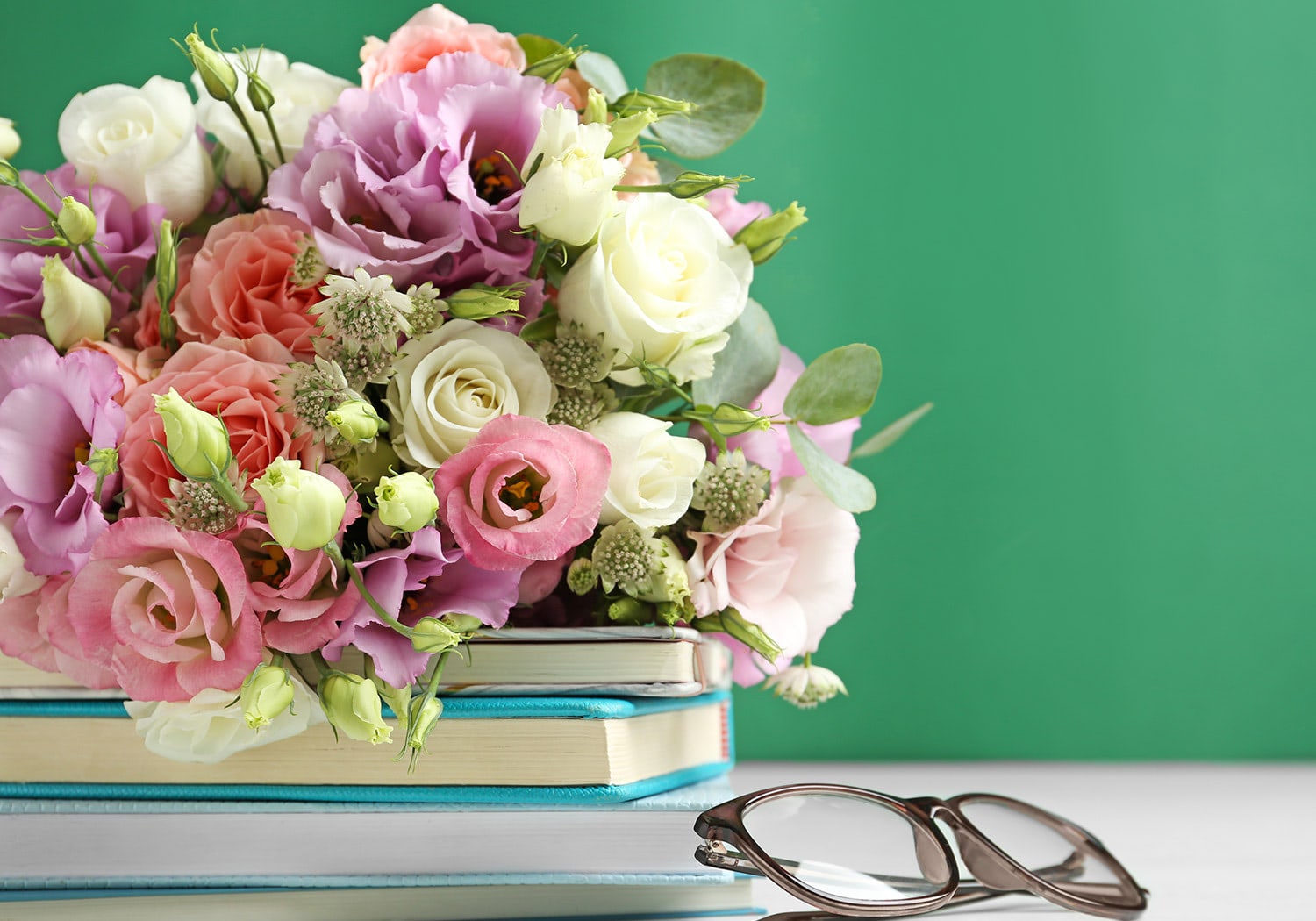 Teacher's Day Bouquet with pink, white and green flowers displayed on stacked books, for a bright spring look.