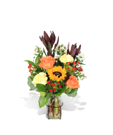 sunset toned fall arrangement with orange roses, sunflowers, and safari sunset in keepsake contemporary container
