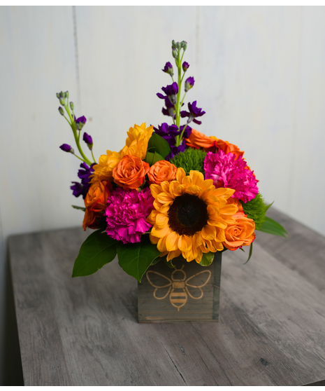 The clear cube has a burlap ribbon with an adorable bee pattern featuring Sunflowers are popping amidst the white hydrangeas
